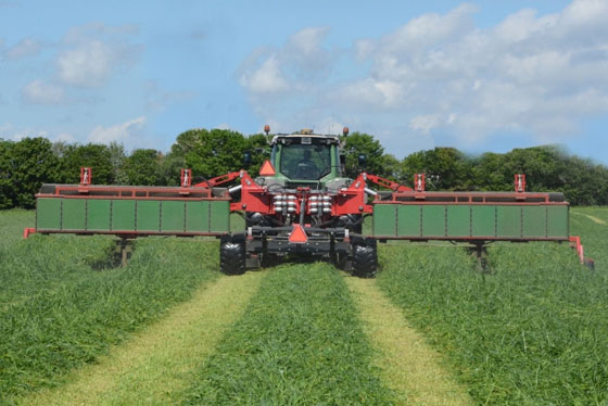 kongskilde mähwerk an traktor auf feld mit viel gras und heu