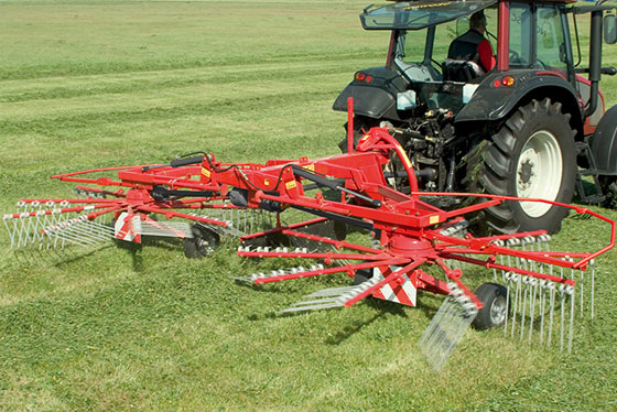 kongskilde schwader an traktor auf feld mit viel gras heu