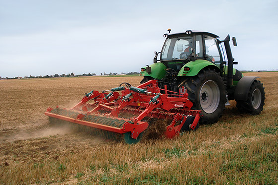 roter kverneland eggen an grünem traktor in einsatz auf einem trockenen feld