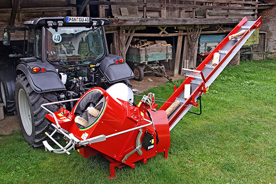 roter unterreiner sägeautomat hinter schwarzem traktor vor einer scheune