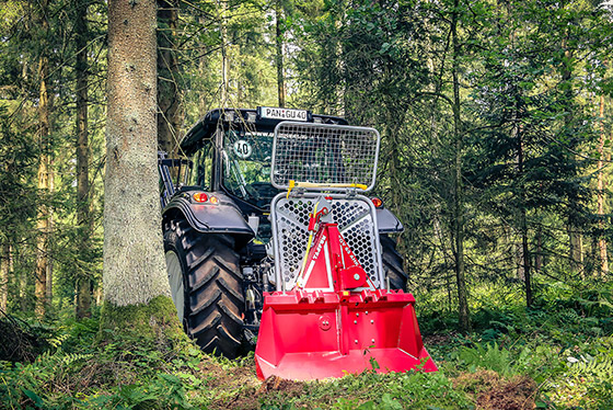 traktor mit anmontierter unterreiner seilweinde steht im grünen wald