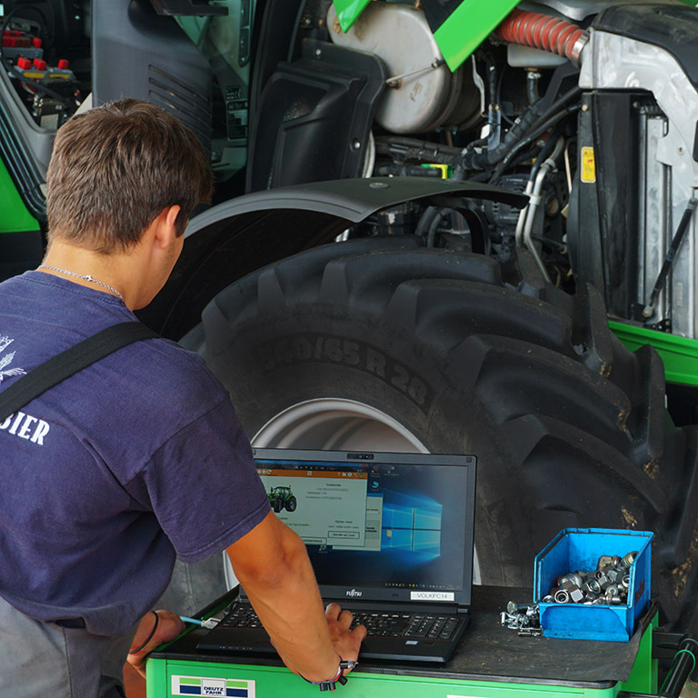 volk landtechnik service mitarbeiter führt diagnose vor einem traktor am laptop durch