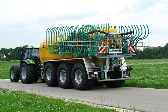 zunhammer pumptankwagen wird von traktor über feldweg gezogen